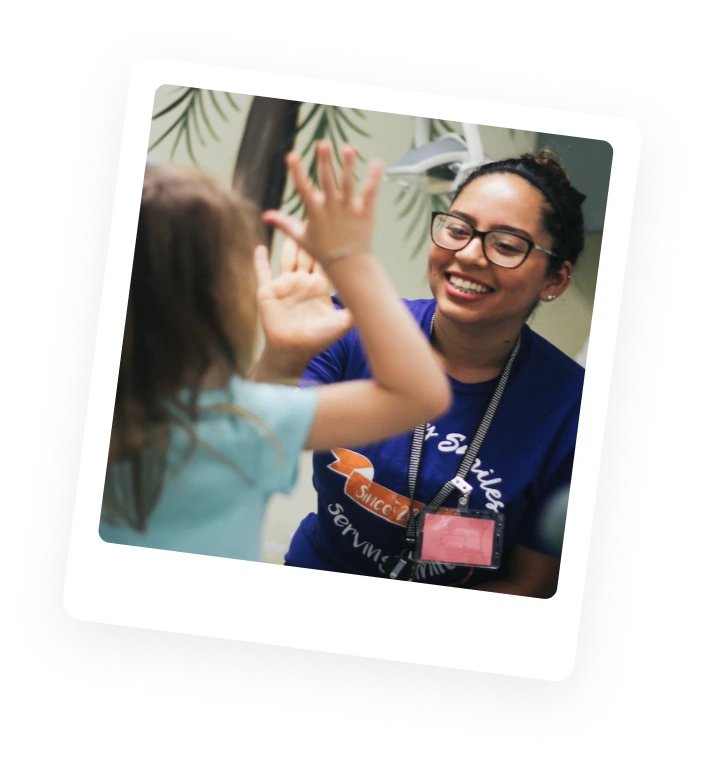 A pediatric dentist high-fiving a patient